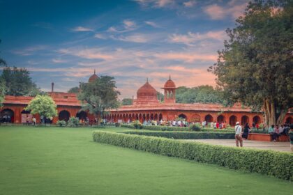 A scenic view of the Red Fort gardens in Delhi, showcasing its historic architecture and lush greenery at sunset.